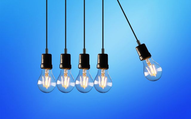 Five hanging light bulbs on blue gradient background, one bulb swinging to the right, decorative image.