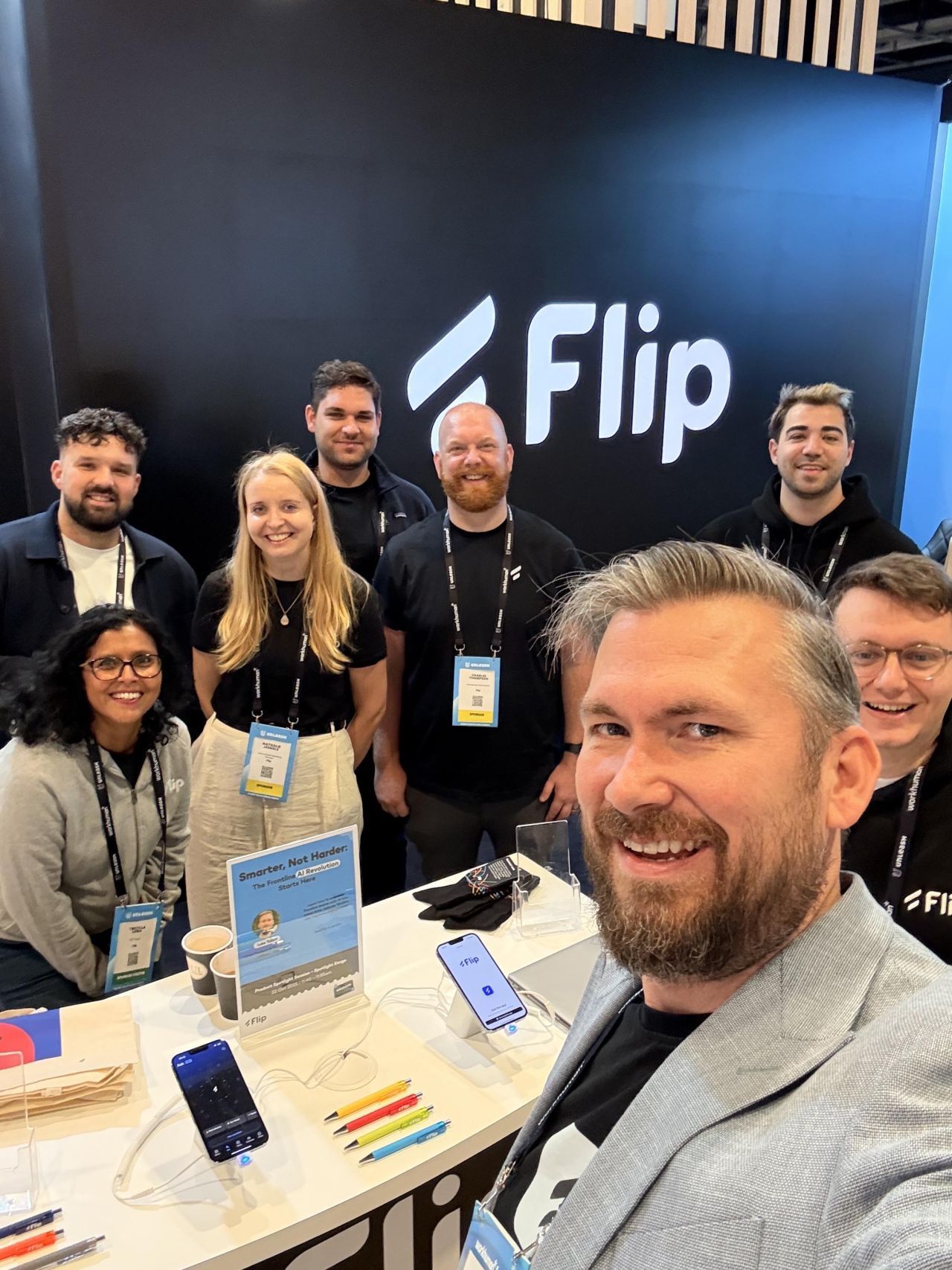 Group at Flip booth with phones and promotional materials.