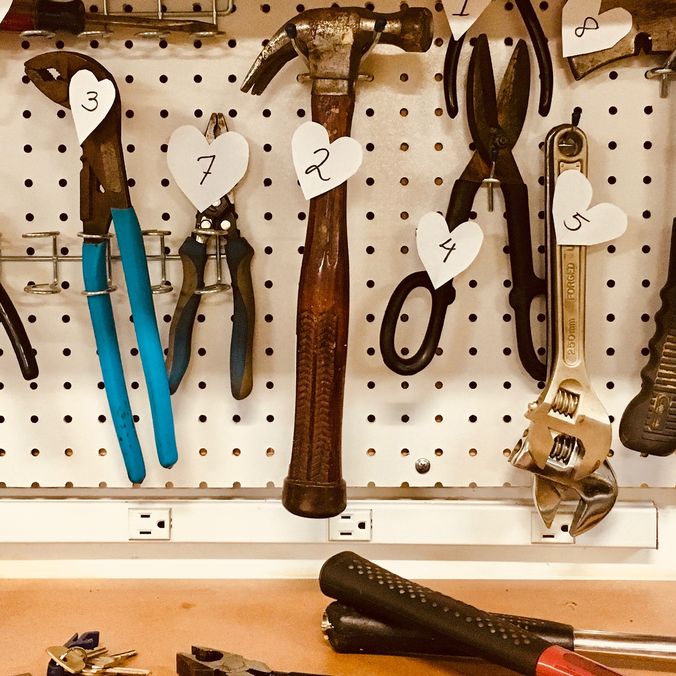 Tools on a pegboard with numbered heart tags.