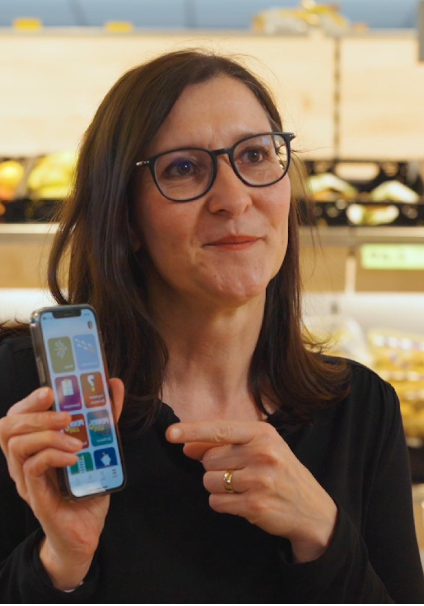 Woman zeigt Mitarbeiter App mit Flip Flows, HR-Portal, Mitarbeiterplattform im Supermarkt.