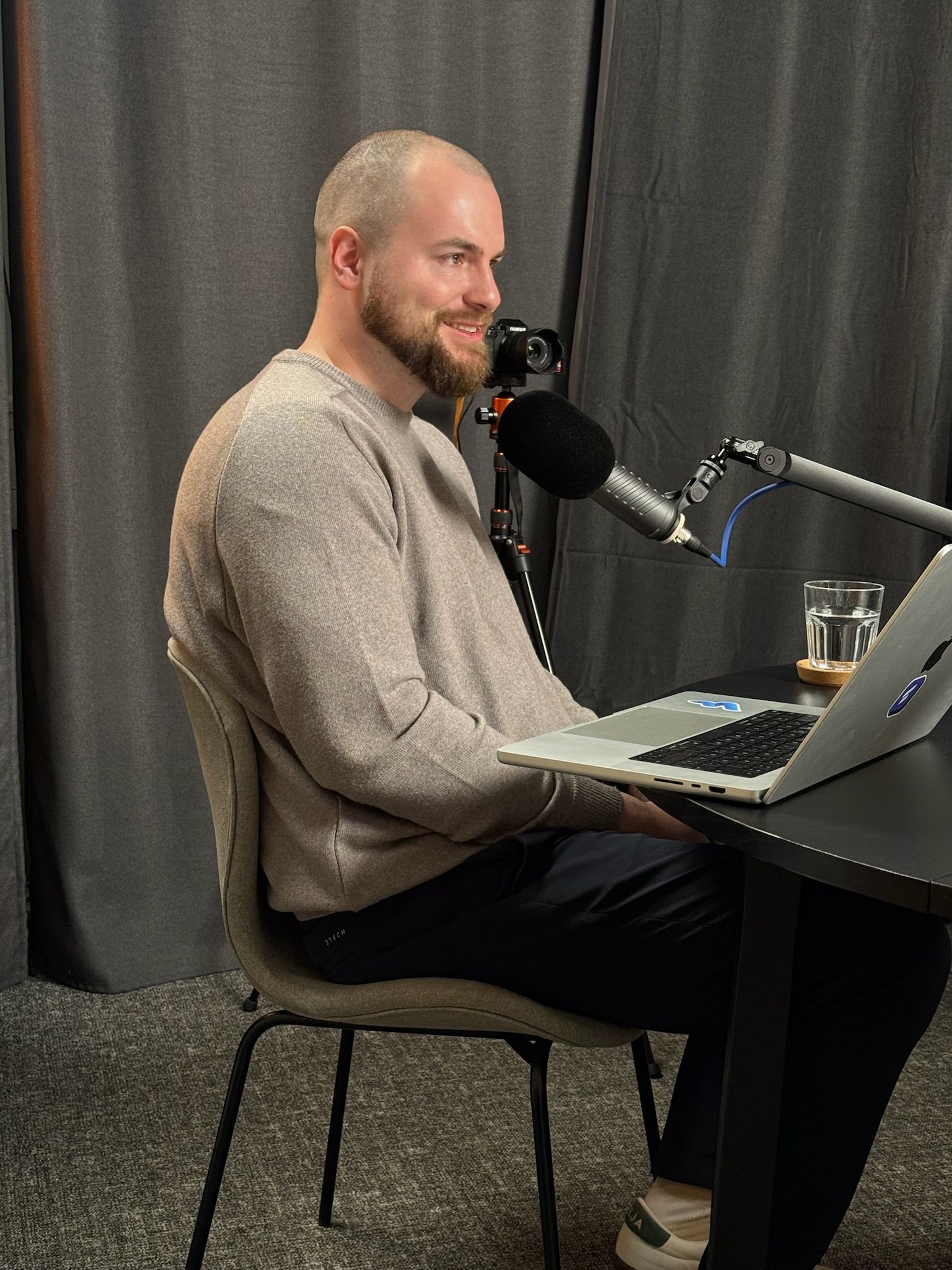 A person with a beard speaking into a microphone during a podcast recording.