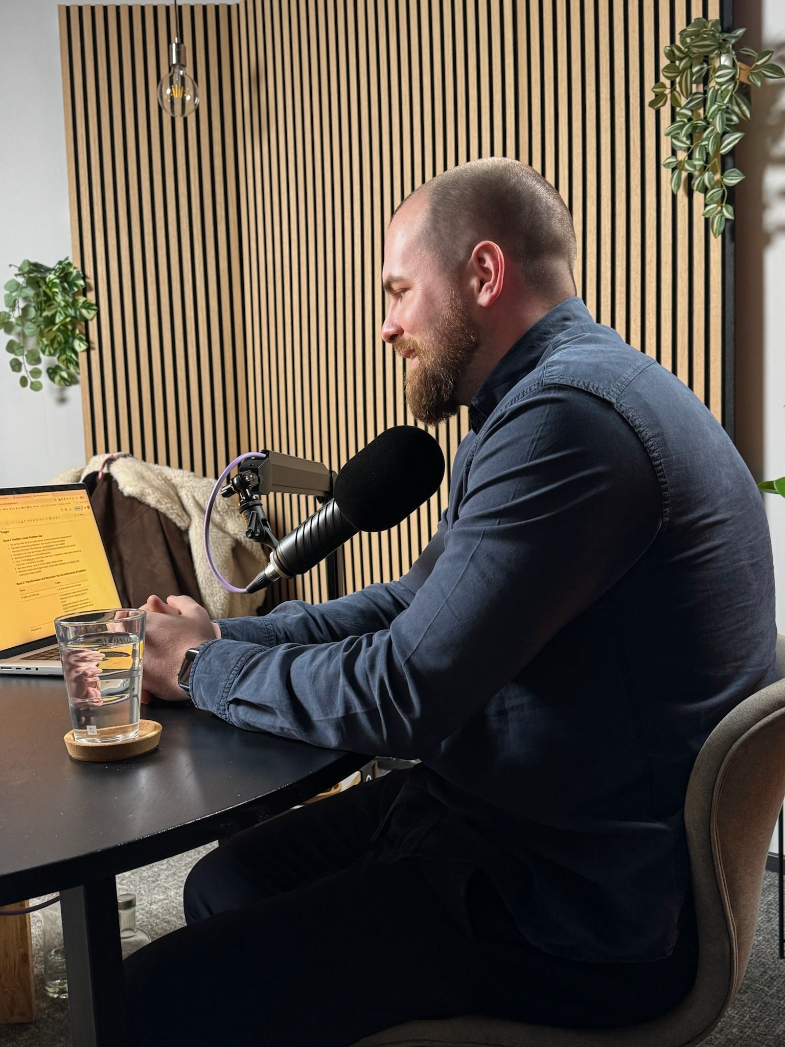 Person sitting at a desk recording a podcast with a microphone.