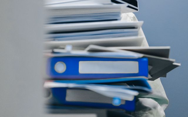 Stack of blue and white office folders and documents, symbolizing HR management workload.