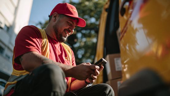 Delivery worker with phone by a van, labeled Logistics