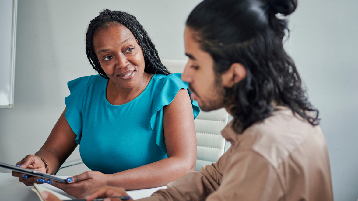 Two people in discussion at a desk, representing workforce management and operations leadership.
