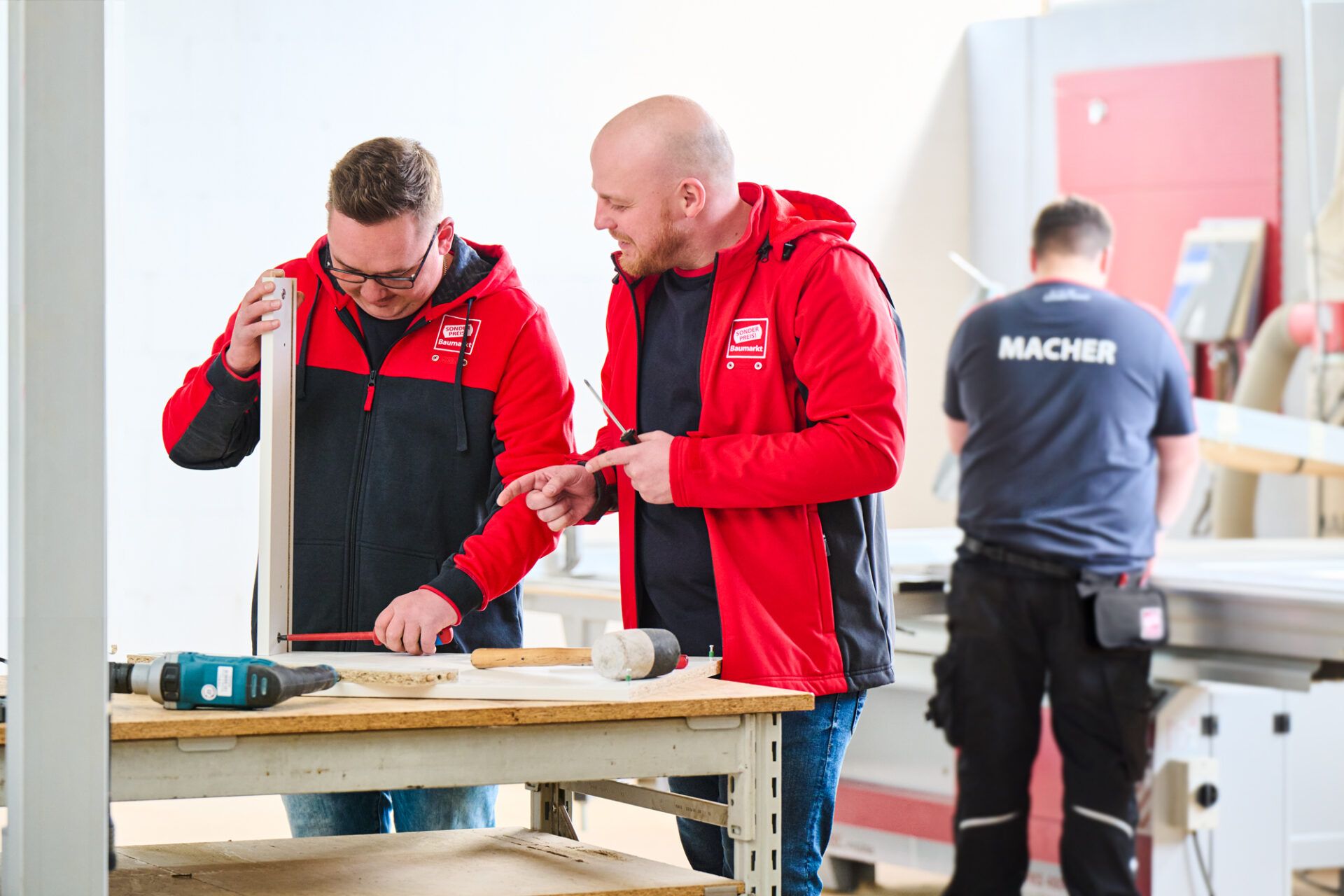 Two men in red jackets working on a construction project.