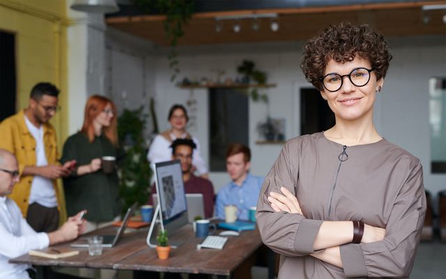 Team leader in modern office with diverse team collaborating at table, fostering employee engagement.