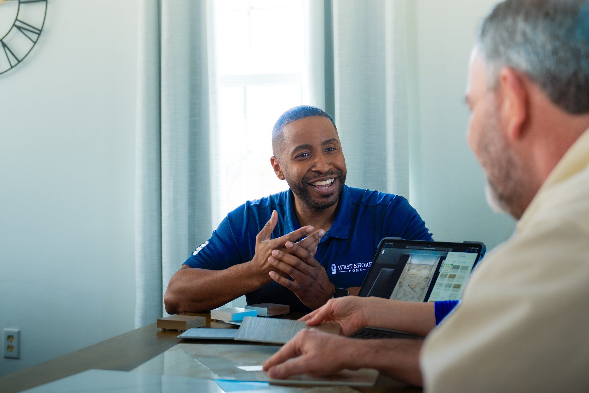 Two men discussing over a tablet at a table.