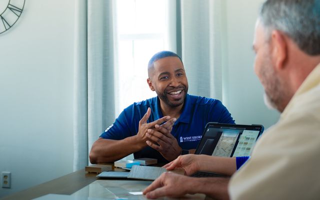 Two men discussing over a tablet at a table.