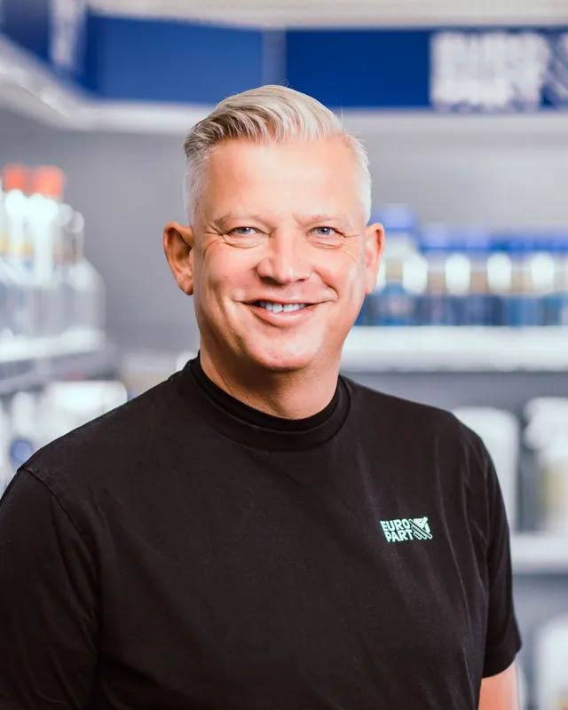 Man smiling in front of Europart shelves with products.