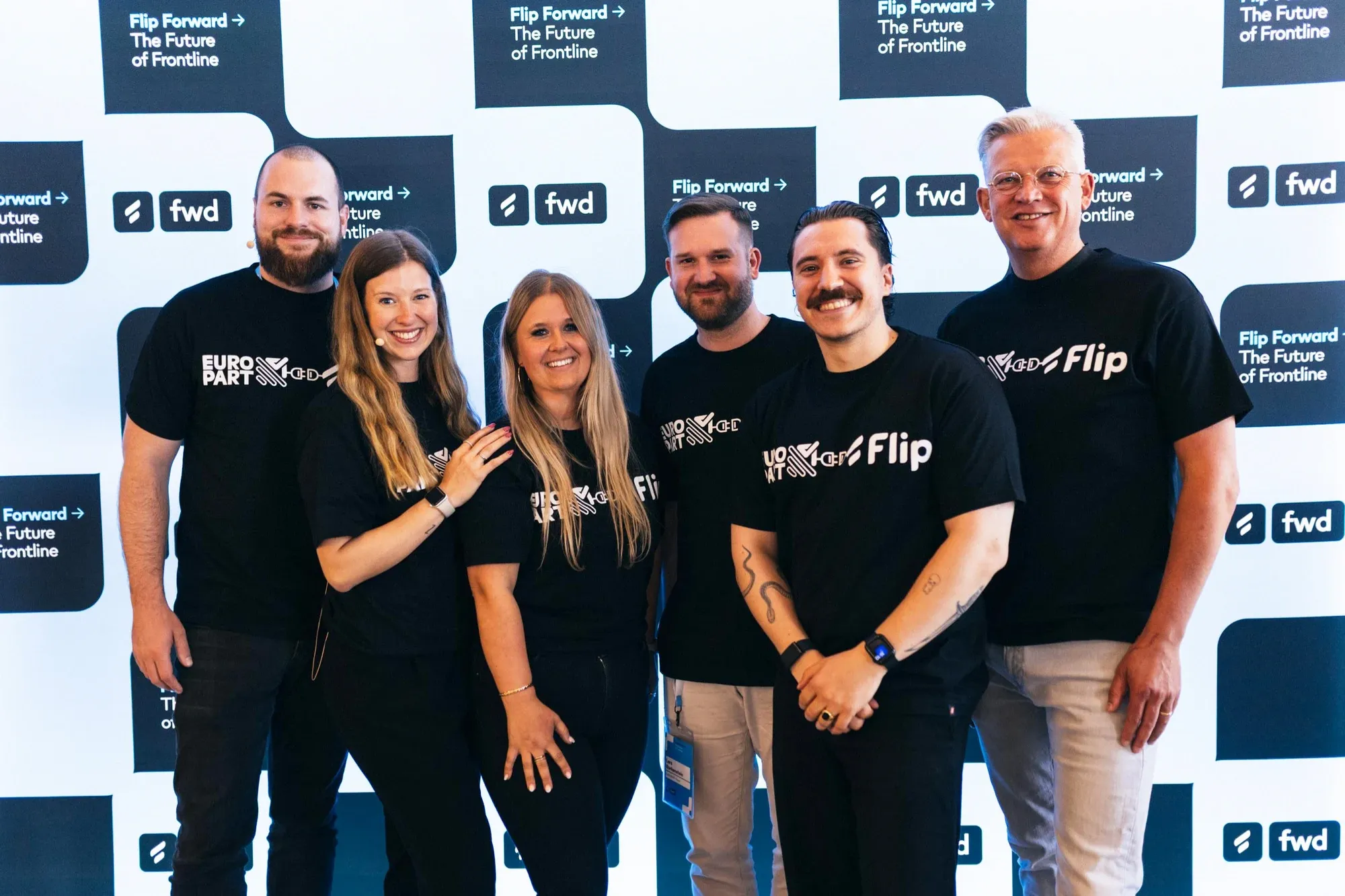 Group of six people in branded shirts at Flip Forward event.