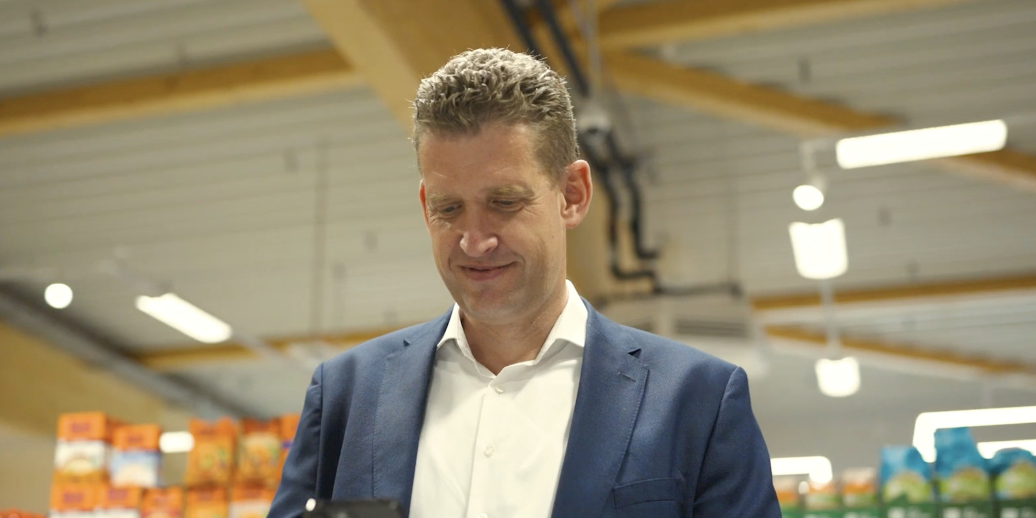 Man using smartphone in a store aisle.