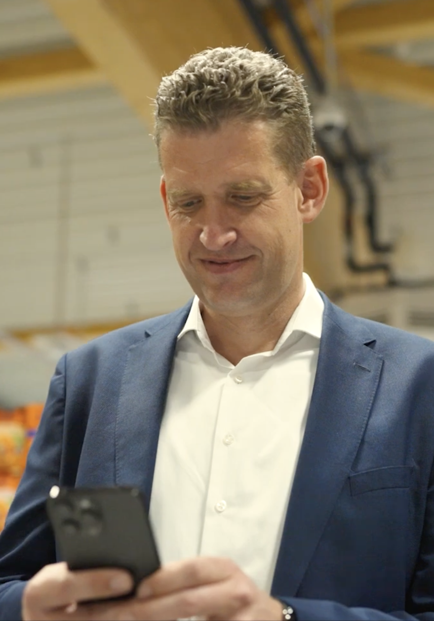 Man using smartphone in a store aisle.