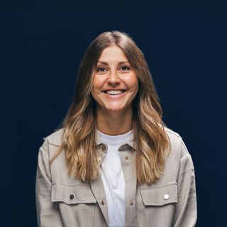 Smiling person against a dark blue background.