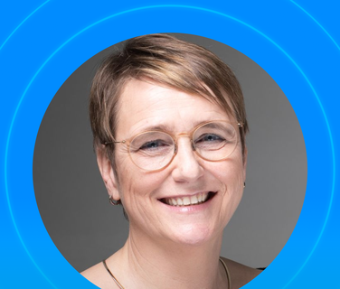 Smiling person with short hair and glasses on a blue background.