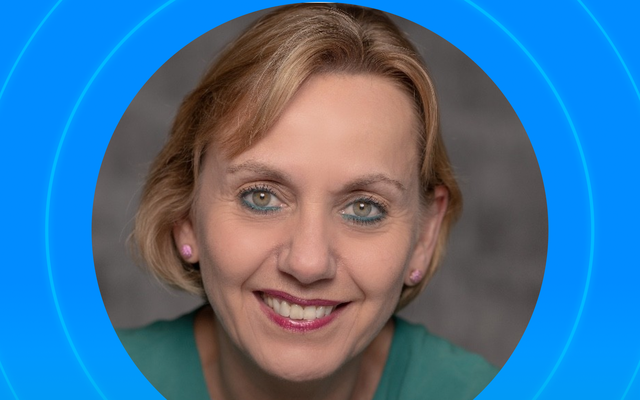 A portrait of a smiling woman on a blue background.