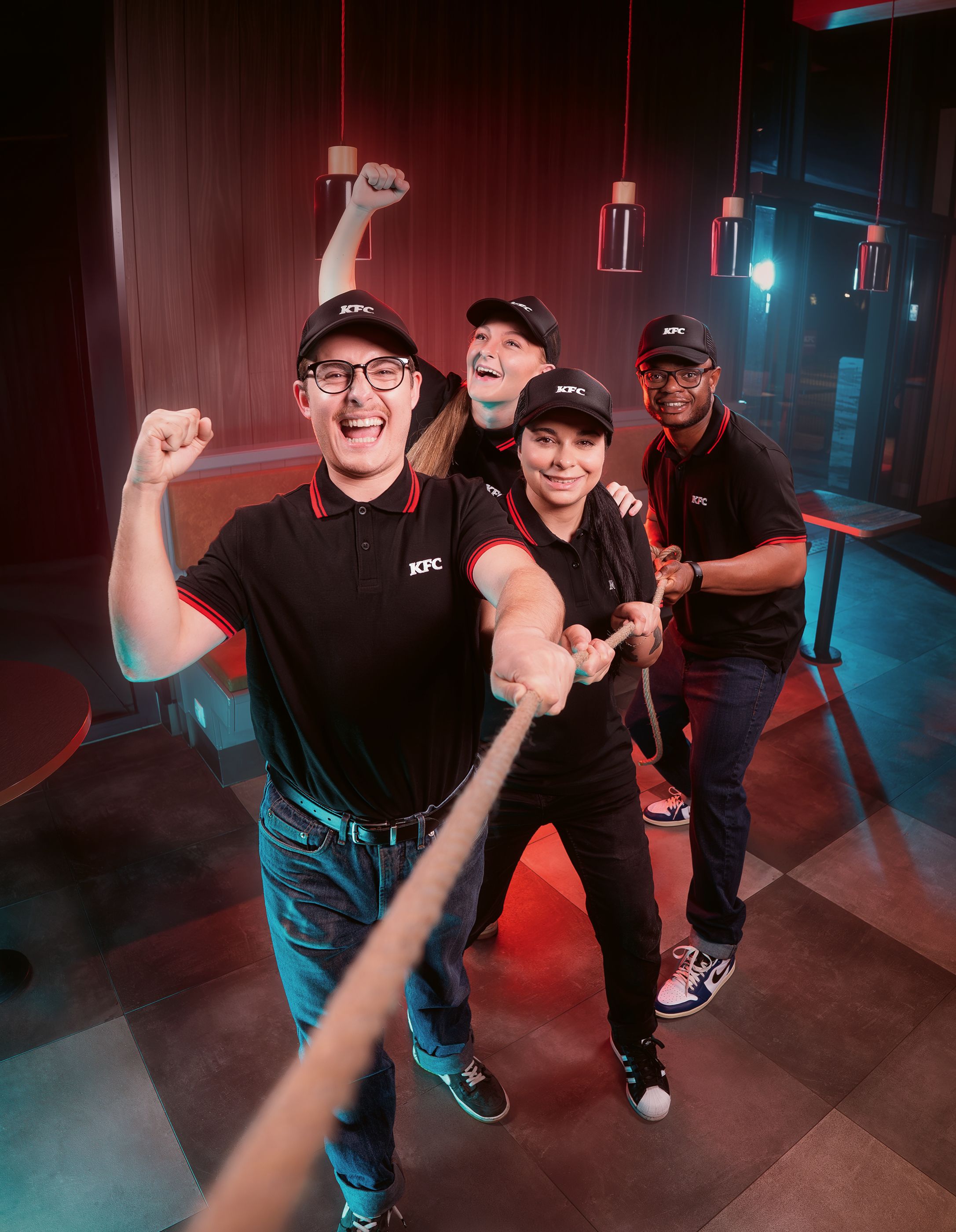 KFC employees pulling on a rope, smiling, wearing uniforms.