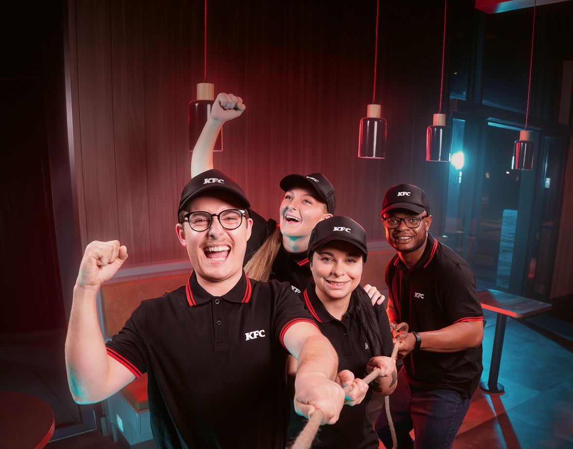 KFC employees pulling on a rope, smiling, wearing uniforms.