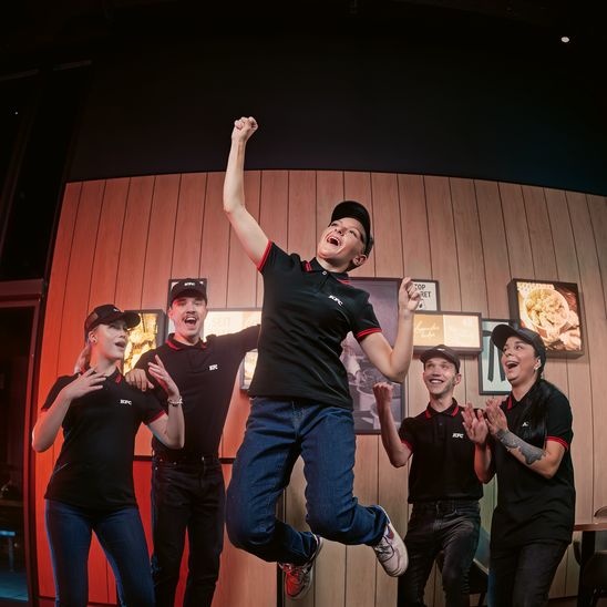 KFC employees celebrating with enthusiasm indoors.