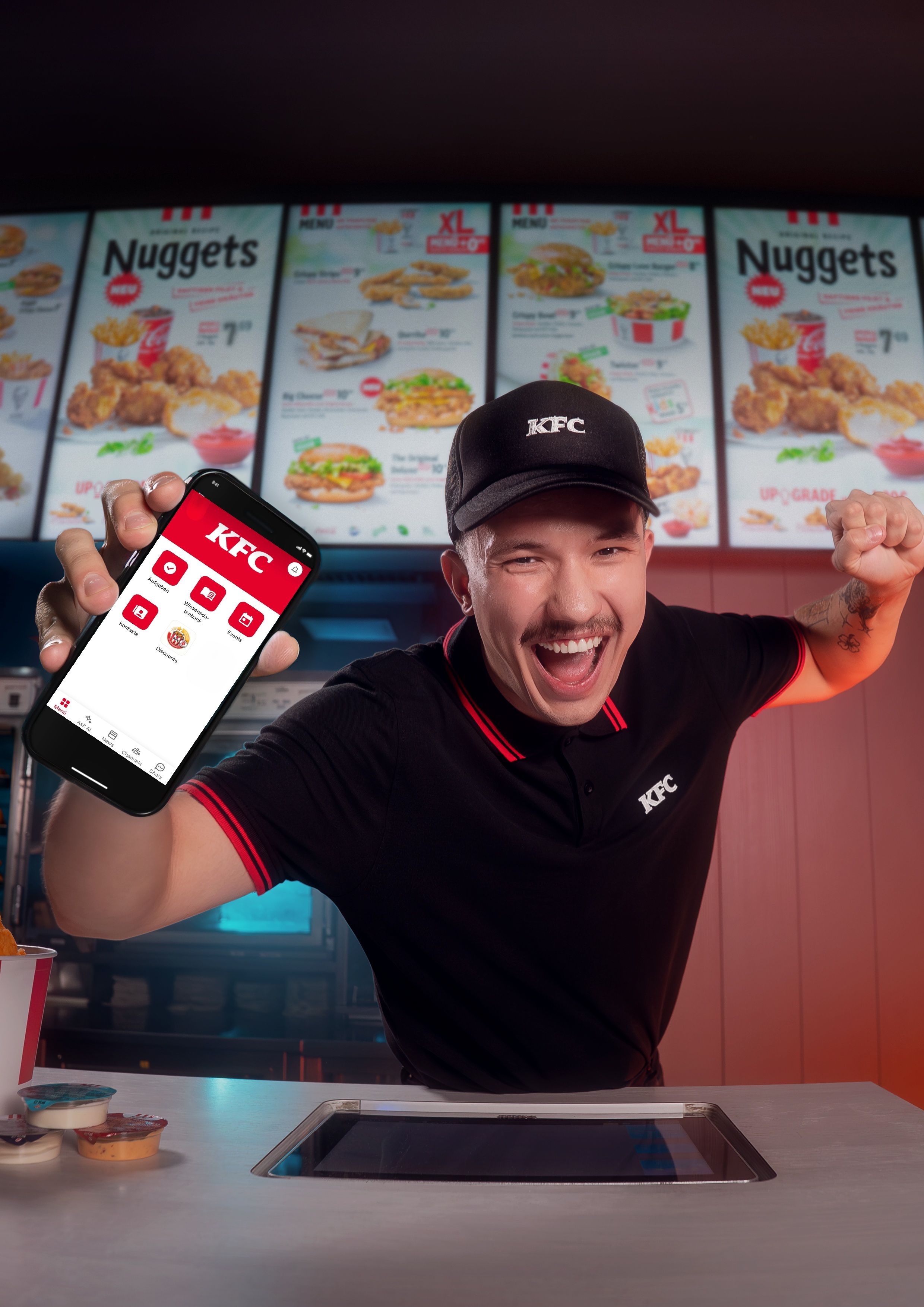 KFC employee excitedly showing a phone app at the counter.