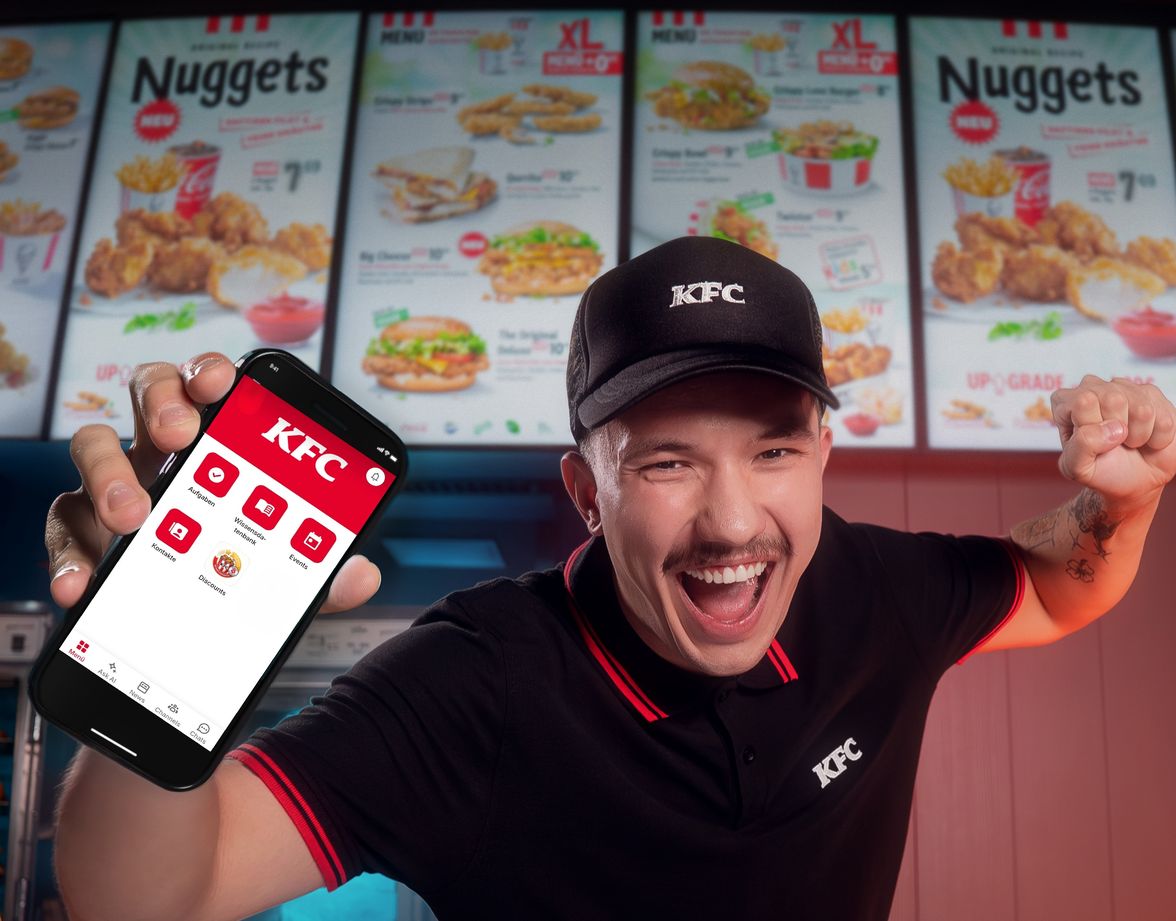 KFC employee excitedly showing a phone app at the counter.