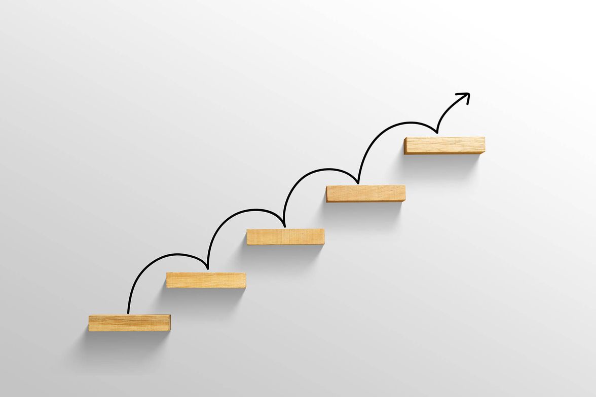 Wooden steps with upward arrow, symbolizing progress.