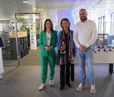 Three people stand in a modern Flip office with Mitarbeiterplattform and Employee Experience Platform visible.