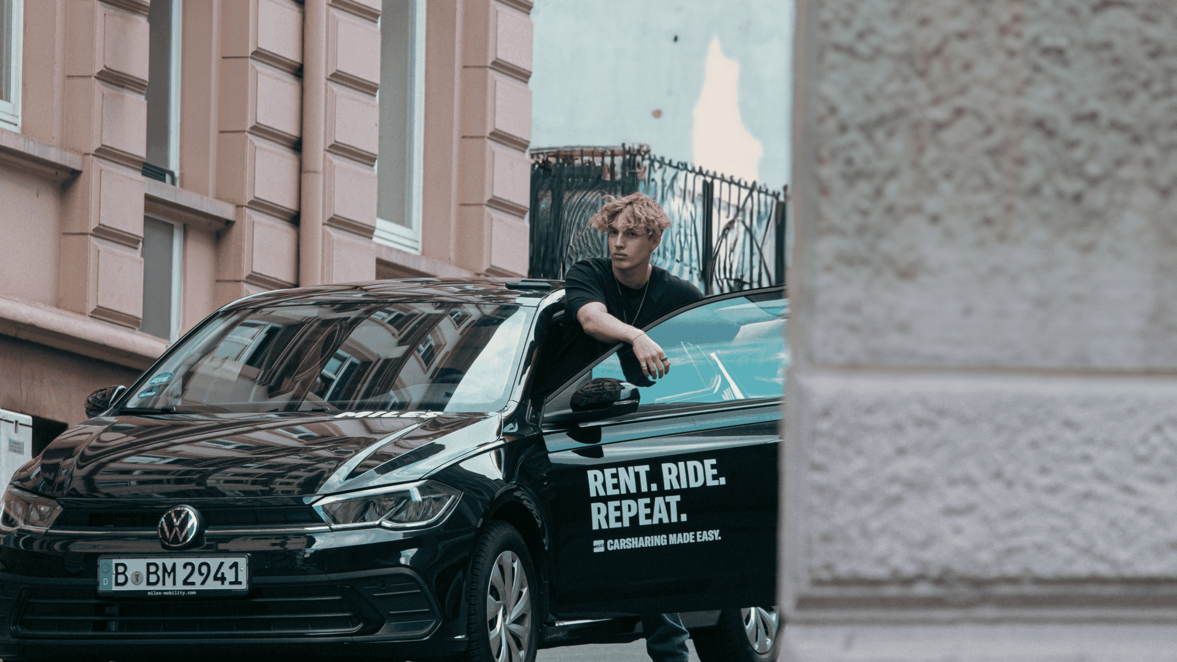 Person standing by a car with Rent. Ride. Repeat. text.