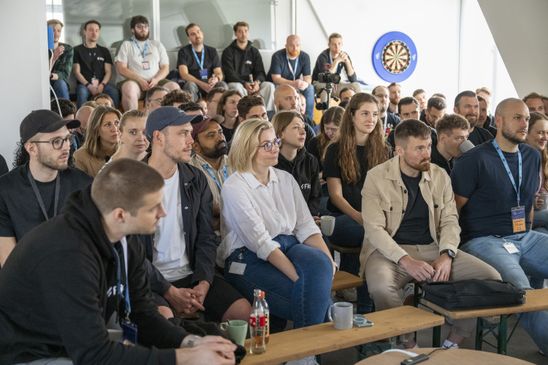 A group of people seated, attentively listening in an indoor setting.