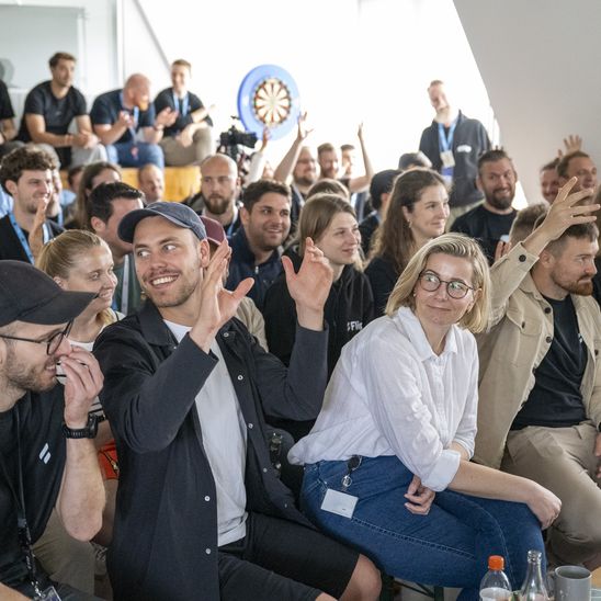 Group of people sitting and raising hands at an event.