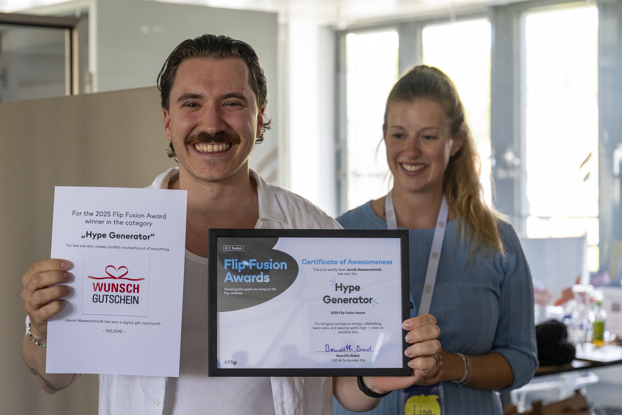 Two people holding a Flip Fusion Awards certificate and gift voucher.