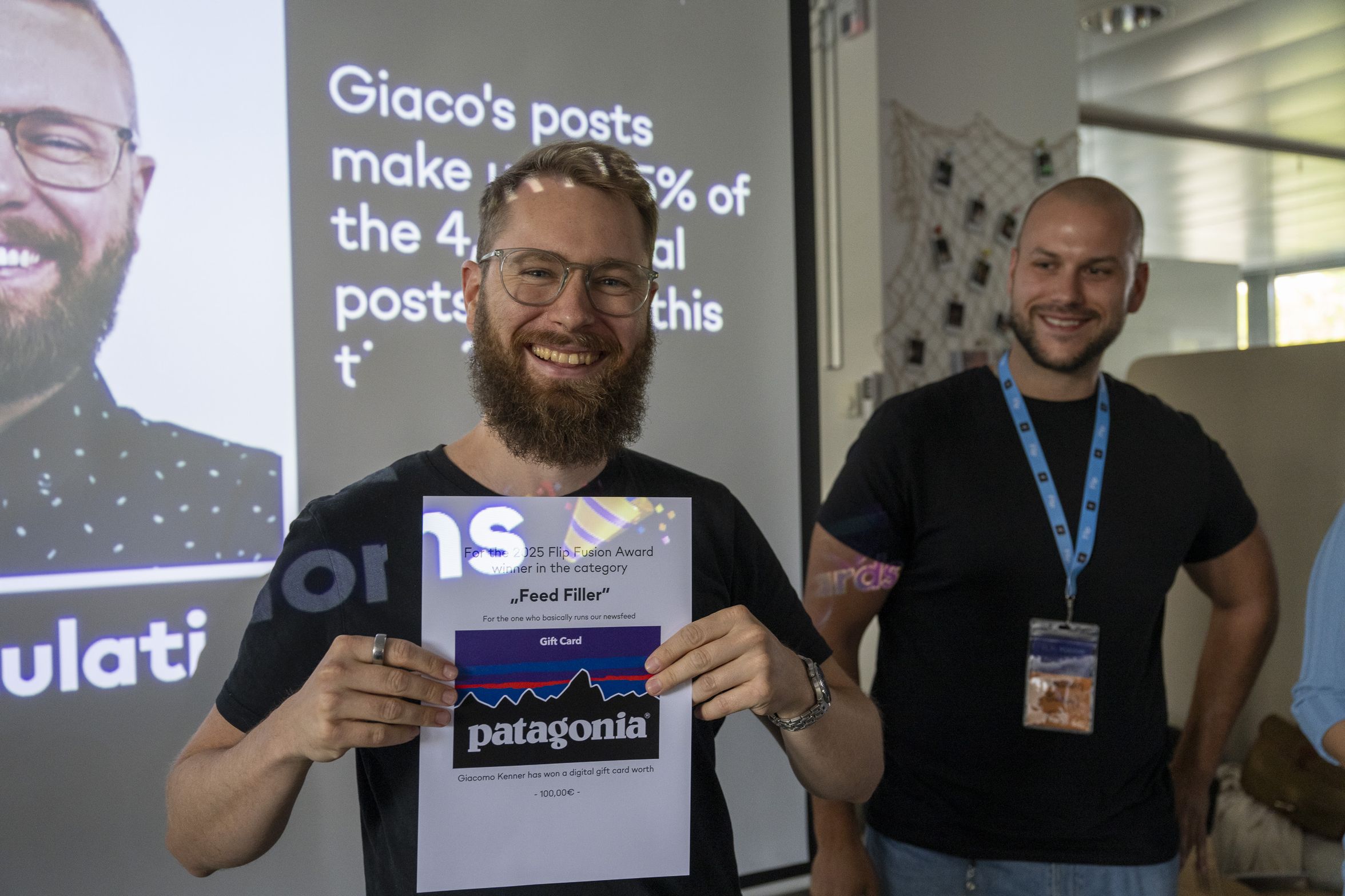 Person holding an award certificate with a smiling face and presentation slide behind.