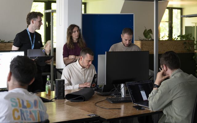 Group of people working around computers in an office setting.