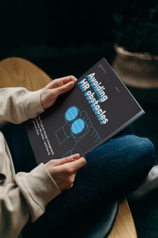 Person holding booklet titled Avoiding HR obstacles. The 5 typical change management mistakes—and how to prevent them.