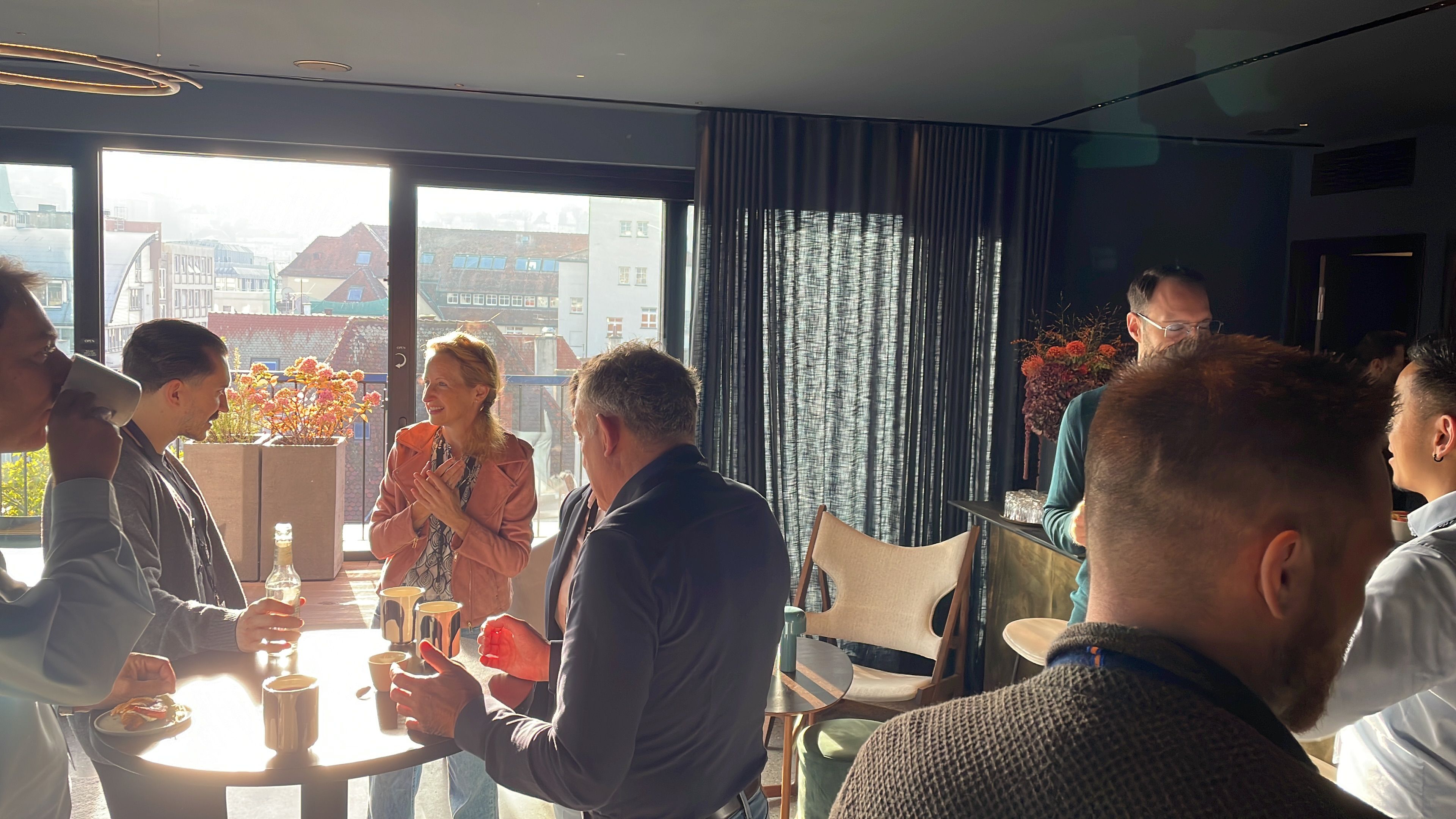 People networking at an indoor event with city view.