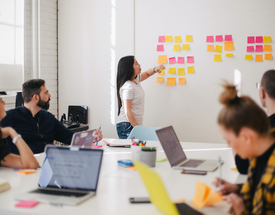 Team collaborates with sticky notes, laptops; empowering frontline via Employee Experience Platform, HR-Portal.