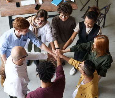 Motivated, diverse team cheering together in a modern office, symbolizing employee engagement.