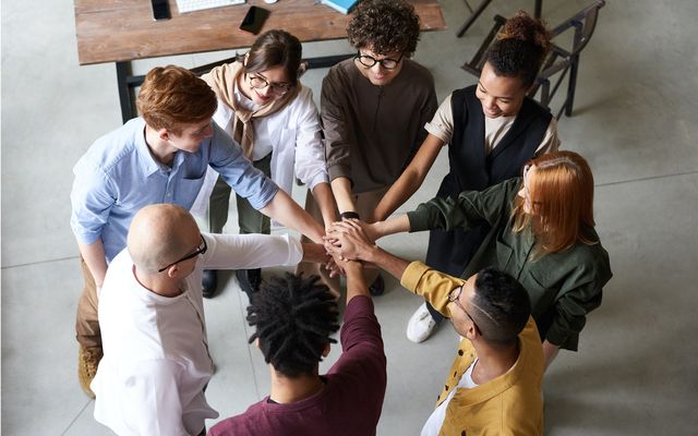 Motivated, diverse team cheering together in a modern office, symbolizing employee engagement.