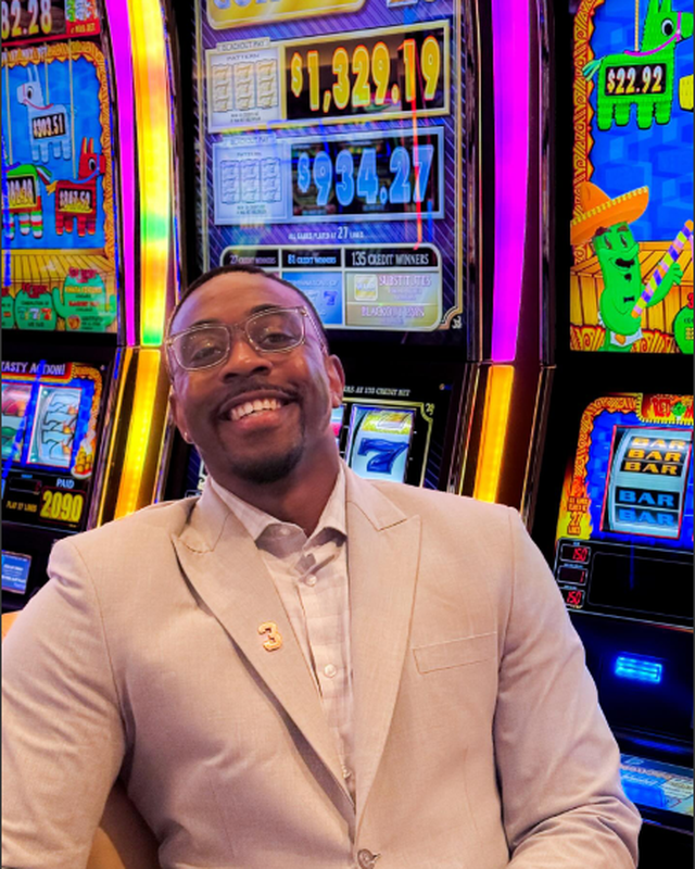 Smiling person in front of slot machines with game displays.