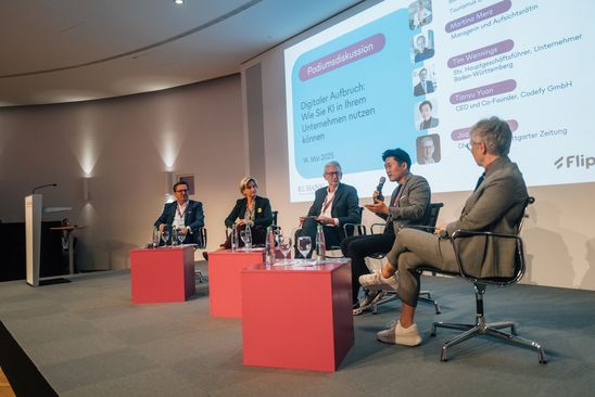 Panel discussion with five speakers on stage about AI use in business.