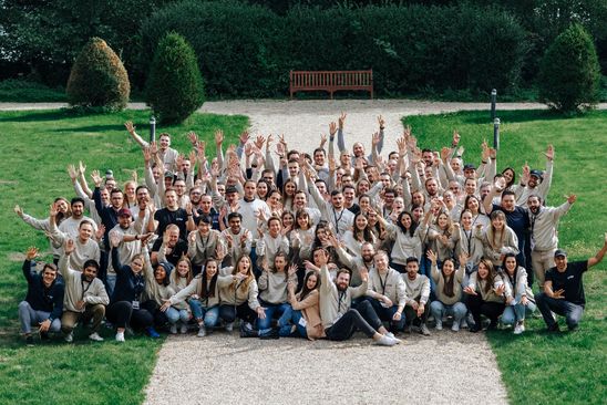 Large group of people outdoors smiling and waving, representing employer branding and team culture.