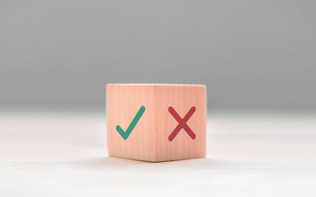 Wooden block with a green check mark and red X, symbolizing decision or evaluation.
