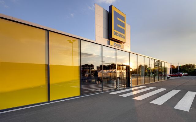 Modern EDEKA supermarket entrance with glass facade, yellow panels, and EDEKA Kolb signage.