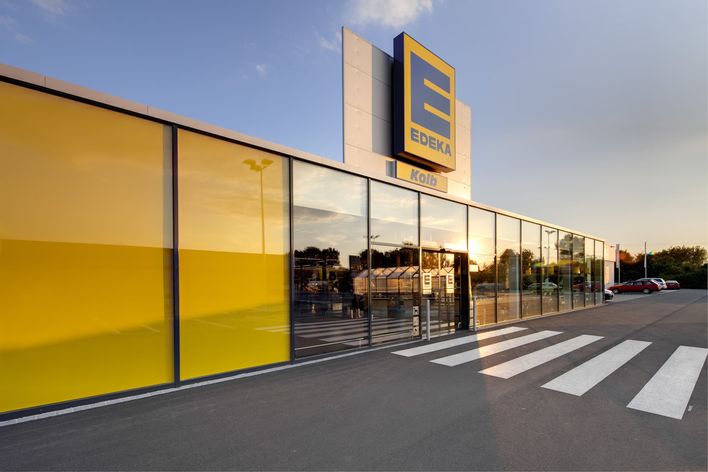 Modern EDEKA supermarket entrance with glass facade, yellow panels, and EDEKA Kolb signage.