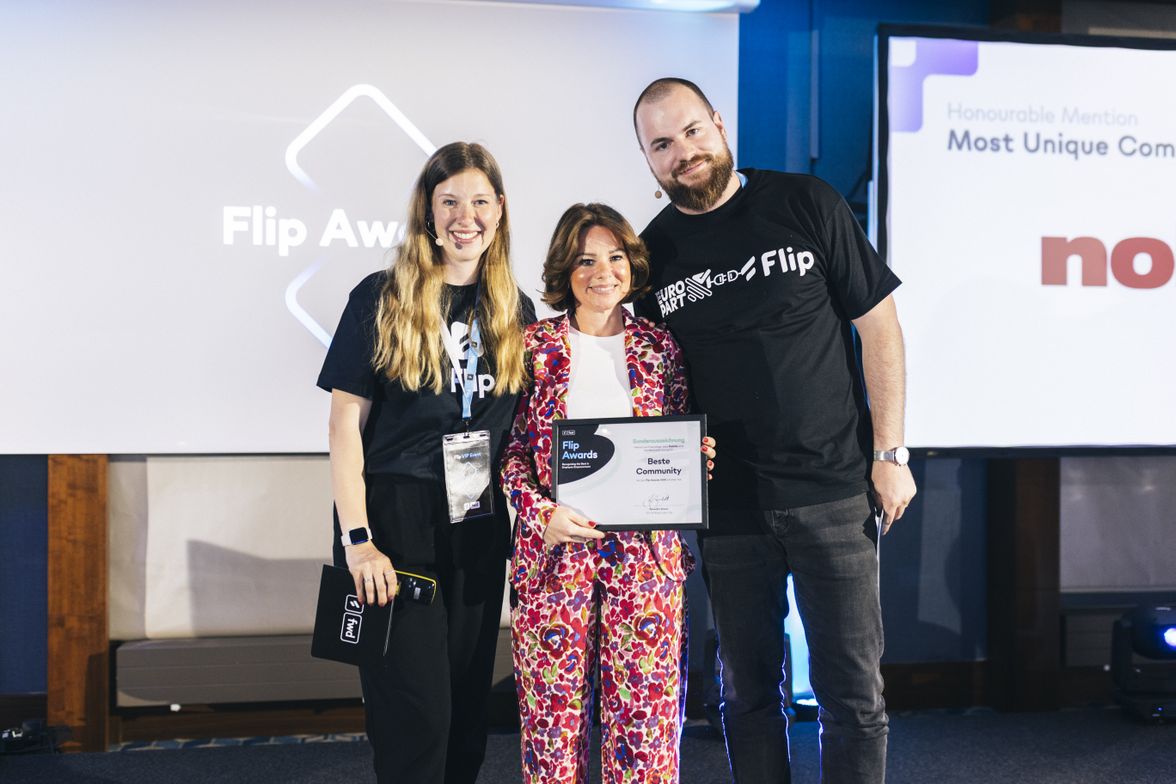Three people at Flip Awards event, holding Flip Awards Beste Community certificate, smiling.