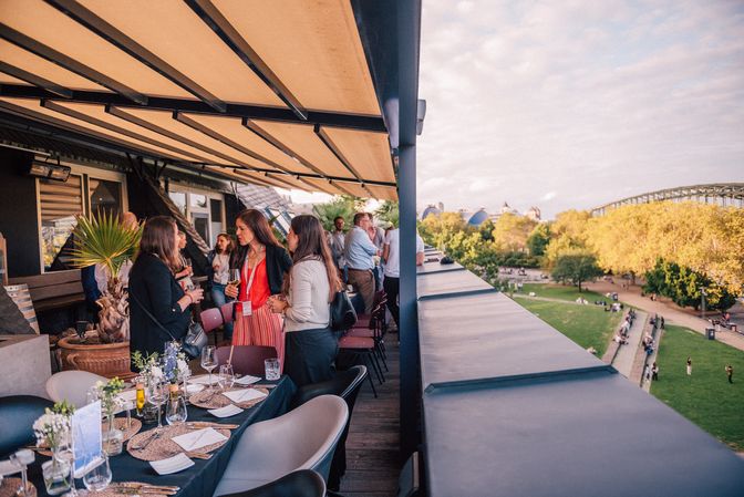 People networking at an outdoor event with tables set for dining.