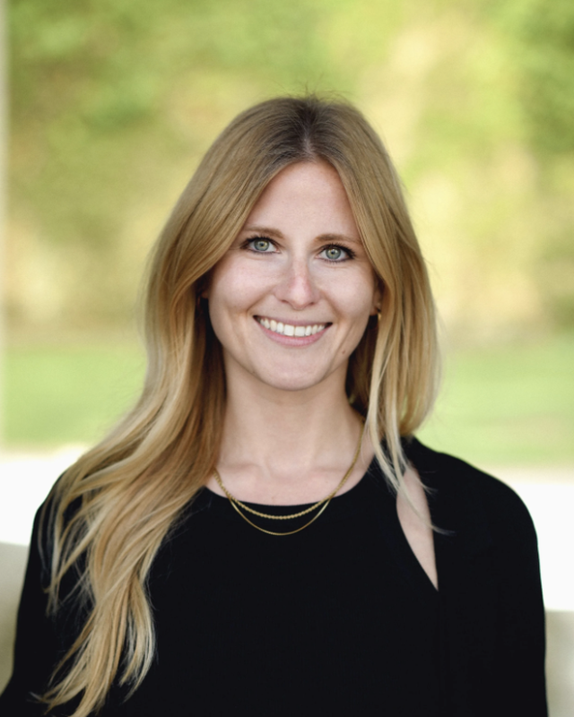 Smiling woman with long blonde hair in a black top.