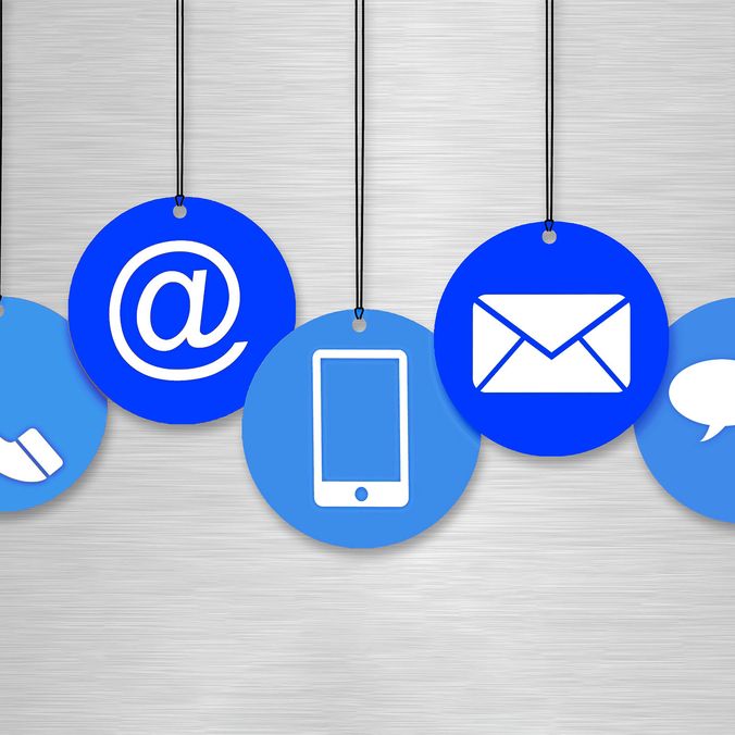 Icons of phone, email, mobile, and chat on blue circles hanging on strings.