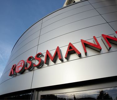 Modern Bürogebäude mit großem ROSSMANN Schriftzug an der Fassade bei blauem Himmel.