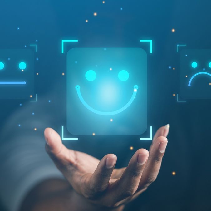 Hand reaching toward digital smiley face icons, symbolizing employee experience and engagement.